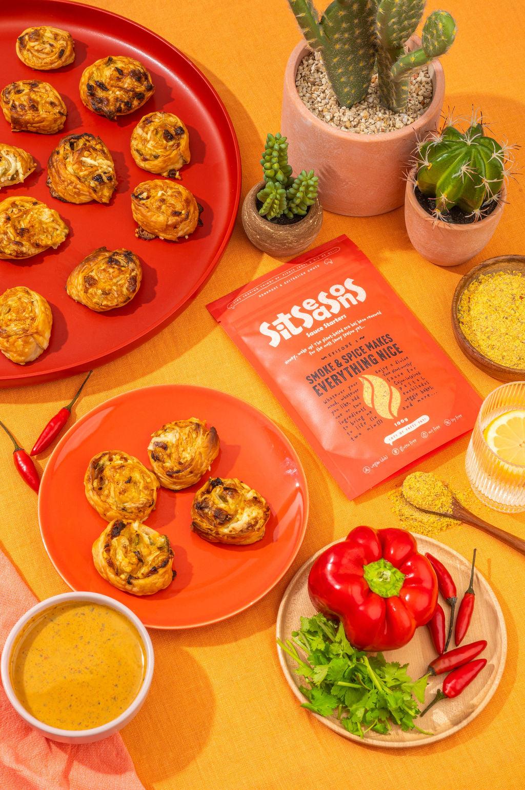Two plates of vegan smoky spicy pizza scrolls with a red sauce packet